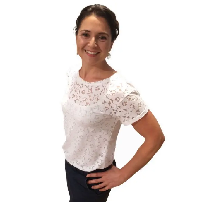 Kylie Grant, founder of Timepeace Advisors, standing confidently in a white blouse with a warm smile.